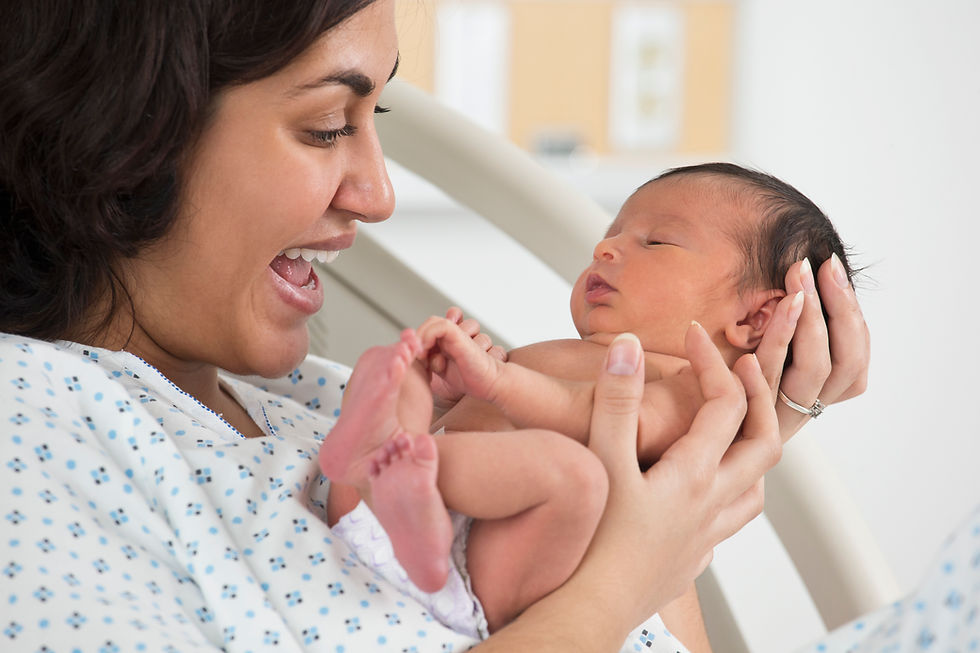 Mother in hospital gown holding and looking at newborn