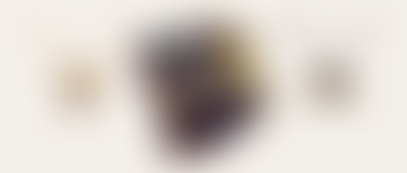 A sculptural wooden ring with gold accents at the center, accompanied by two pendant necklaces, illustrating modern organic jewelry trends on a neutral background