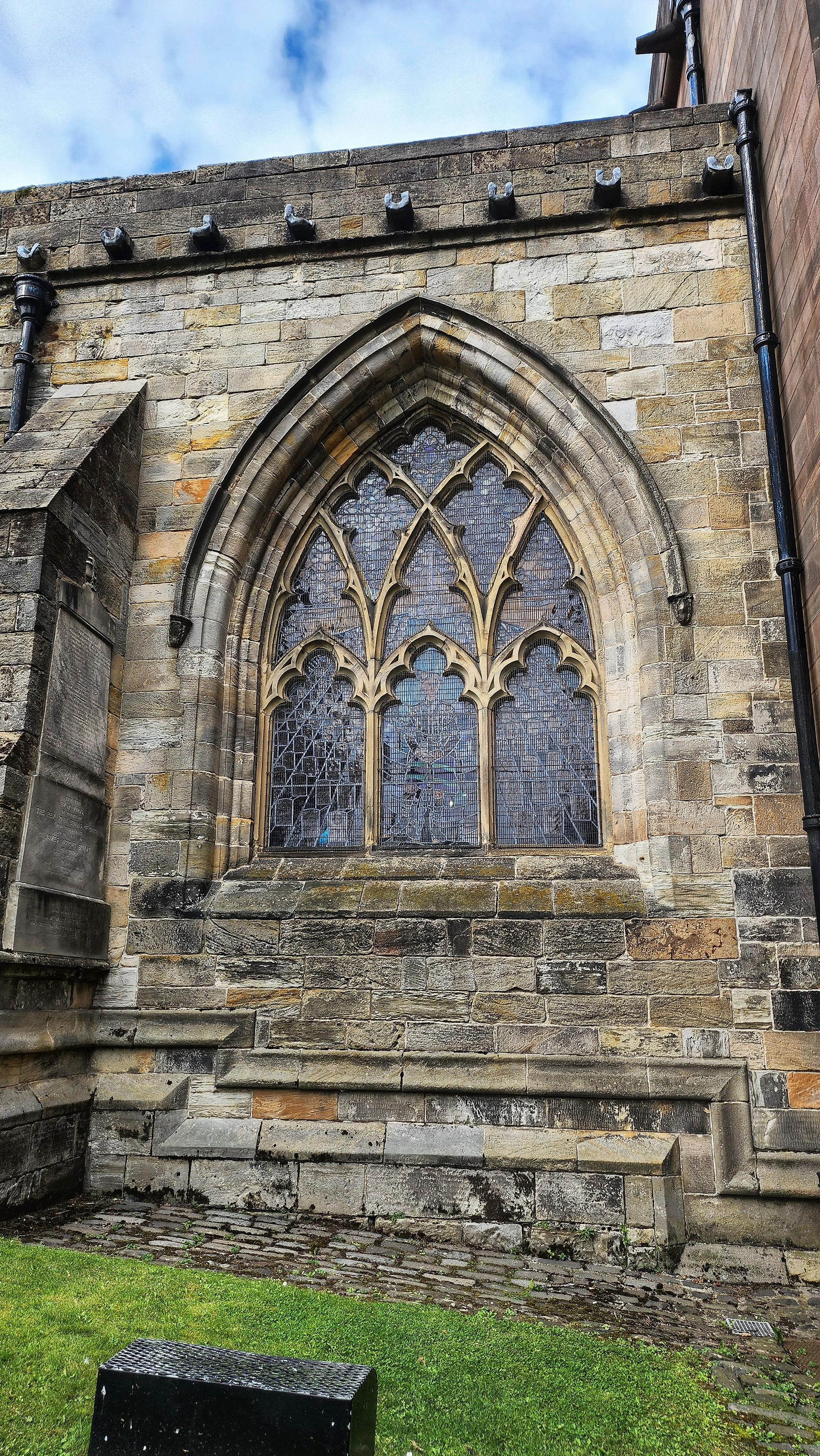 Looking at a stained glass window from the outside, framed by stone 