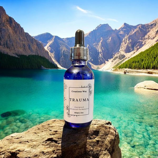 Olive Leaf 'TRAUMA' blue dropper bottle on a rock by a mountain lake