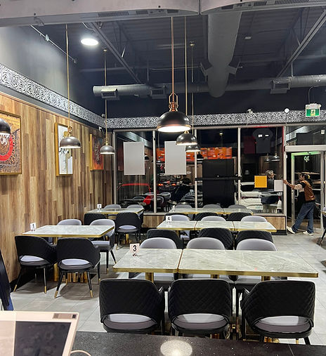 Restaurant interior with tables, chairs, and bright lighting. Various signs are displayed My Site 3