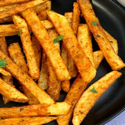 Plate of seasoned fries, close-up shot, golden fried deliciousness, ready to eat.