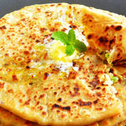 Delicious paratha stack topped with butter and mint leaves, close-up shot.