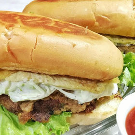 Two delicious sandwiches with egg, meat, and vegetables, with a sauce.