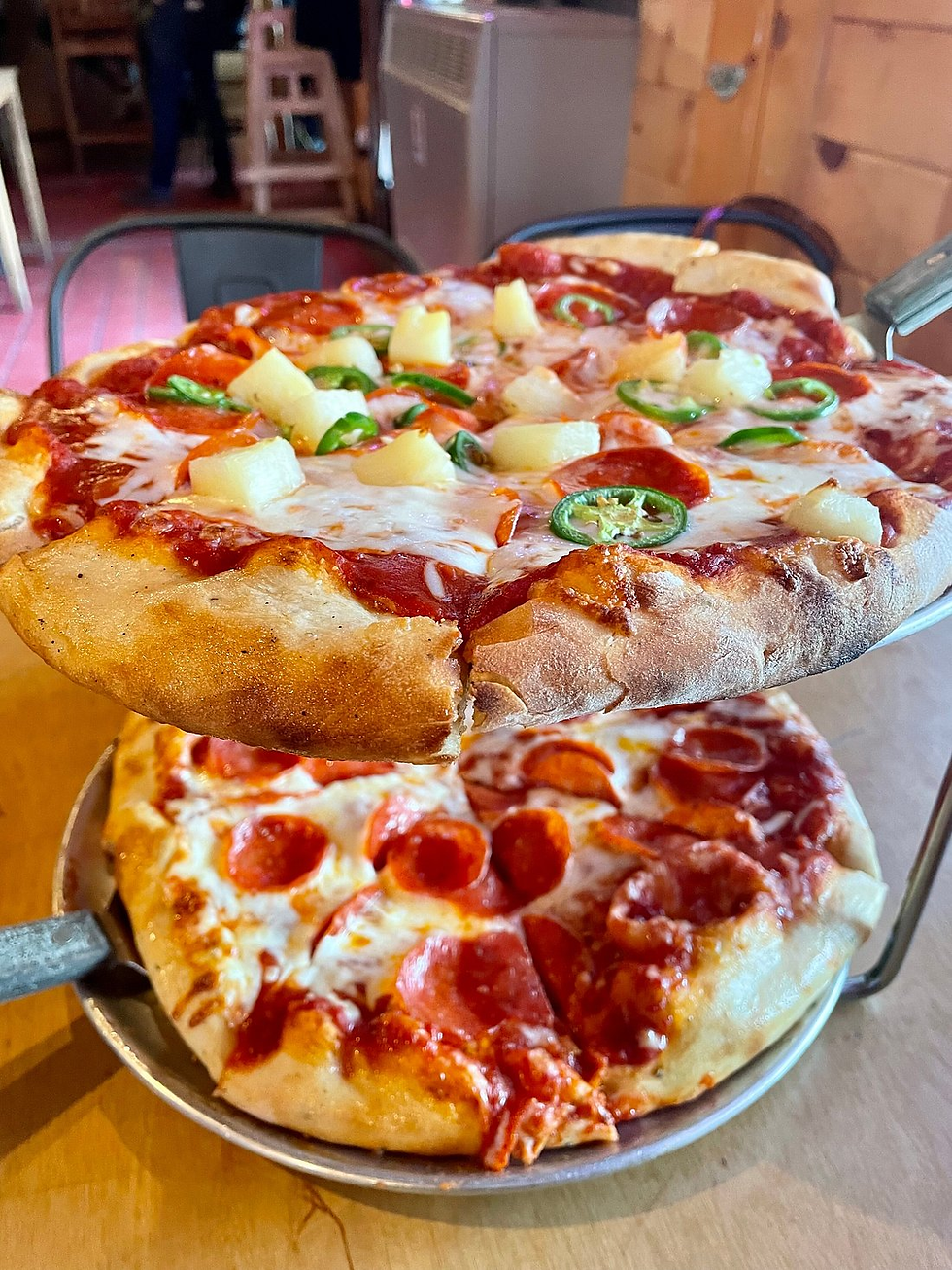Freshly baked wood-fired pizzas topped with pepperoni, pineapple, and jalapeños at Panorama Pizza Pub in Denali National Park, Alaska.