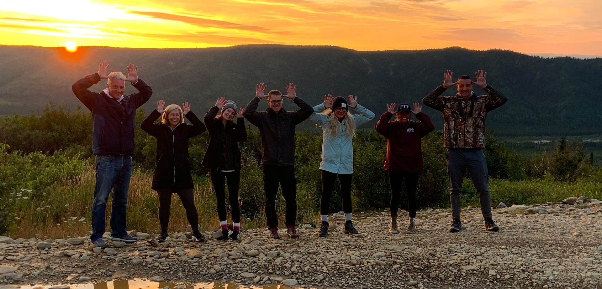 roup of friends posing at sunset during a Denali Midnight Sun ATV Adventure in Alaska
