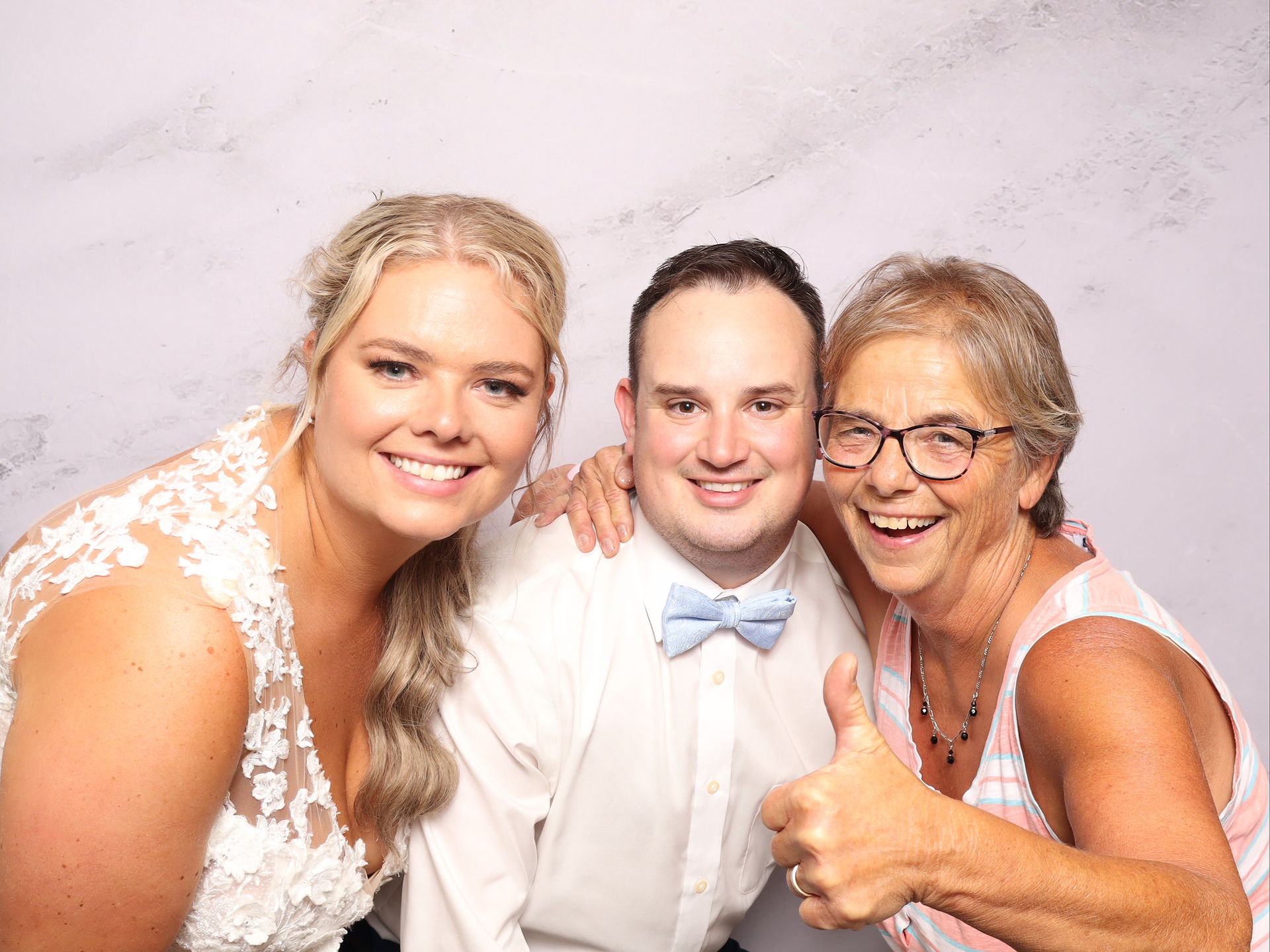 The newlywed couple and their wedding guest smile for a photo
