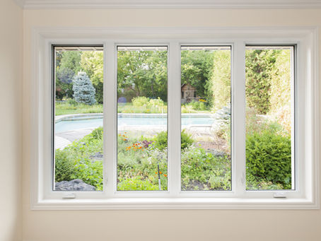 A set of white-framed casement windows offering a clear view of a lush backyard with a pool. The windows allow abundant natural light and improve energy efficiency.