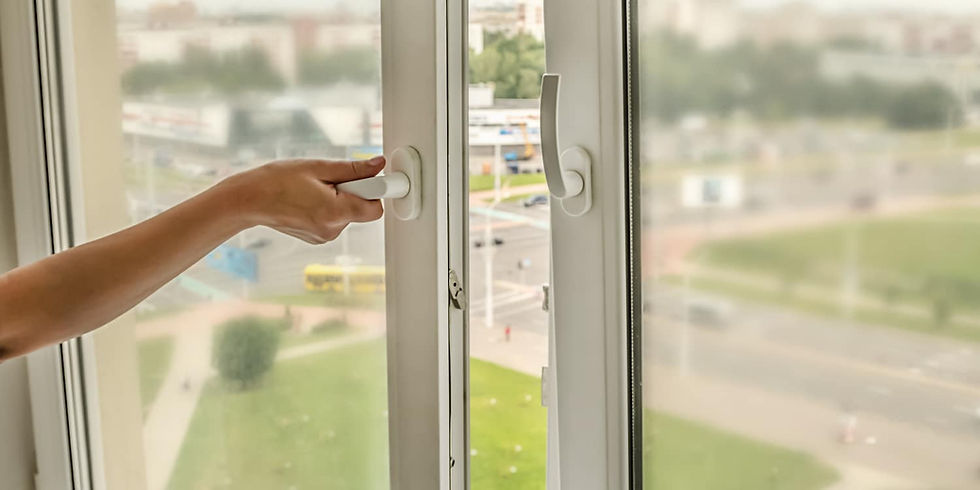 A person opening a modern sliding window with a white frame, overlooking an urban landscape.