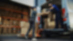 A delivery worker handing a box to another employee in a warehouse, symbolizing seamless vendor-managed inventory replenishment.