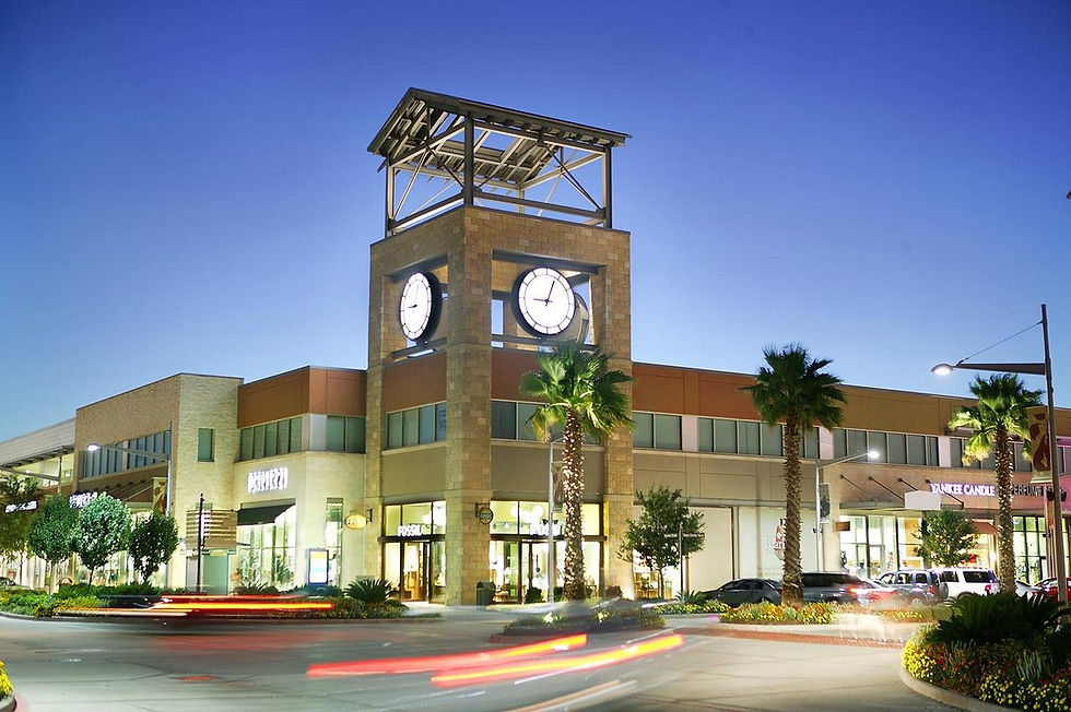 Pearland Town Center clock tower and shopping plaza lit up at dusk.