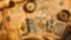 Tarot antiguo sobre mapa sepia: libro Historia del Tarot, brújula y cartas El Loco, La Sacerdotisa, La Rueda de la Fortuna, La Muerte y El Mundo.
