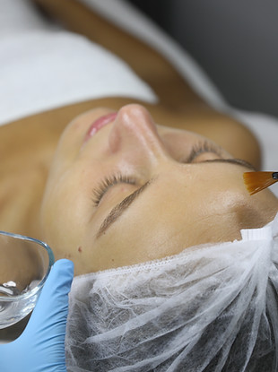 Cosmetologist applying cosmetic product for chemical peeling on client's face in salon