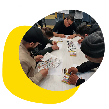 A group of people chatting and doing crafts on a table next to it is a dialog bubble icon with a heart inside.