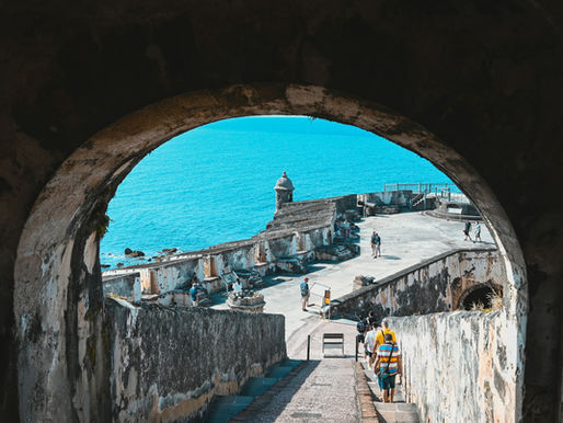 Looking through an old window opening at an old fort and the ocean beyond.