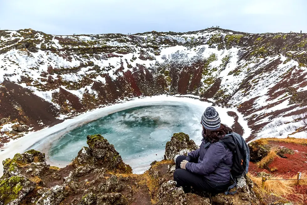 Persona sentada observando un cráter volcánico helado en Islandia