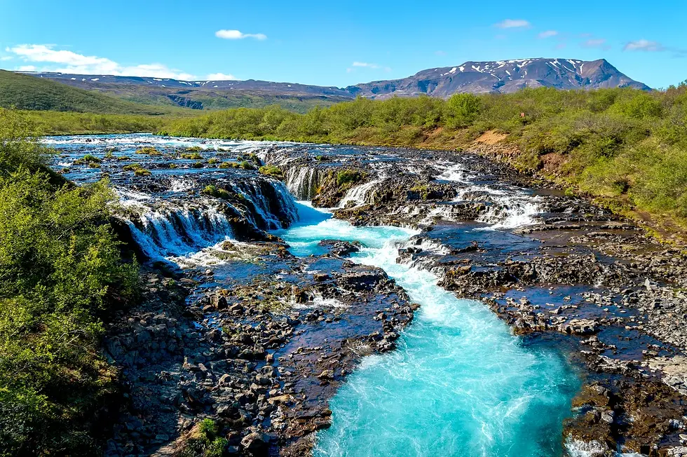 Cascada Bruarfoss en verano, con paisajes verdes y cielo despejado