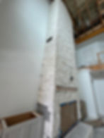 Tall white stone fireplace under renovation in a home.