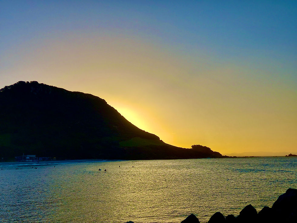 image of a mountain surrounded by ocean with the sun behind it.