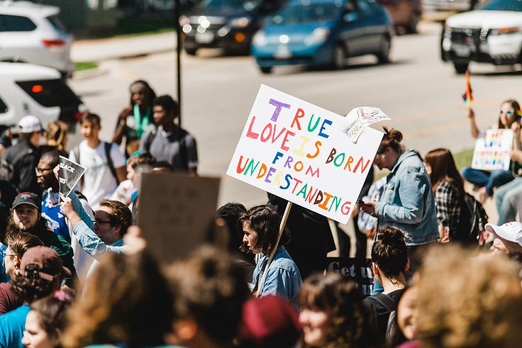 Protest marchers carrying signs, most prominent sign is "True love is born from understanding."