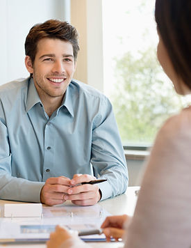 Smiling man in a light blue shirt talks during a meeting