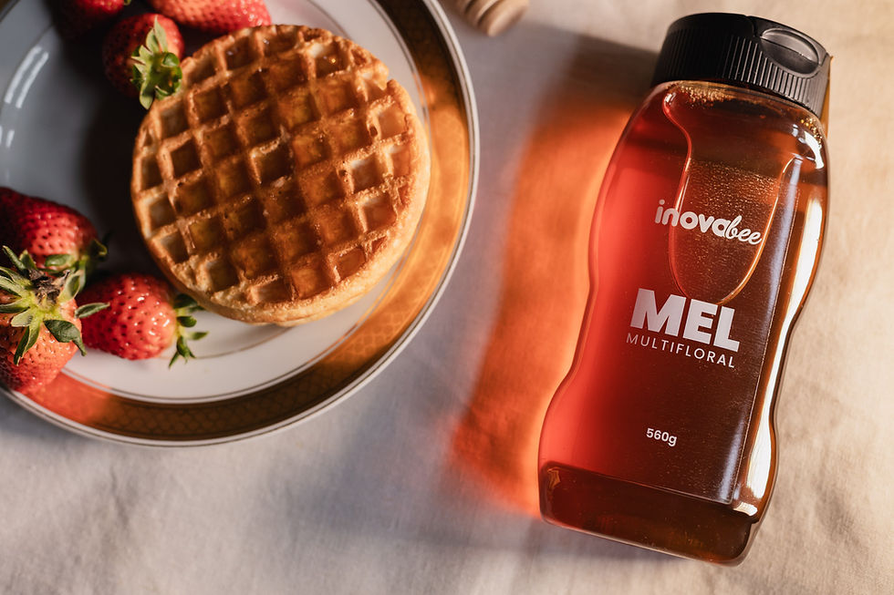 Bisnaga de mel ao lado de um prato com waffle e morangos