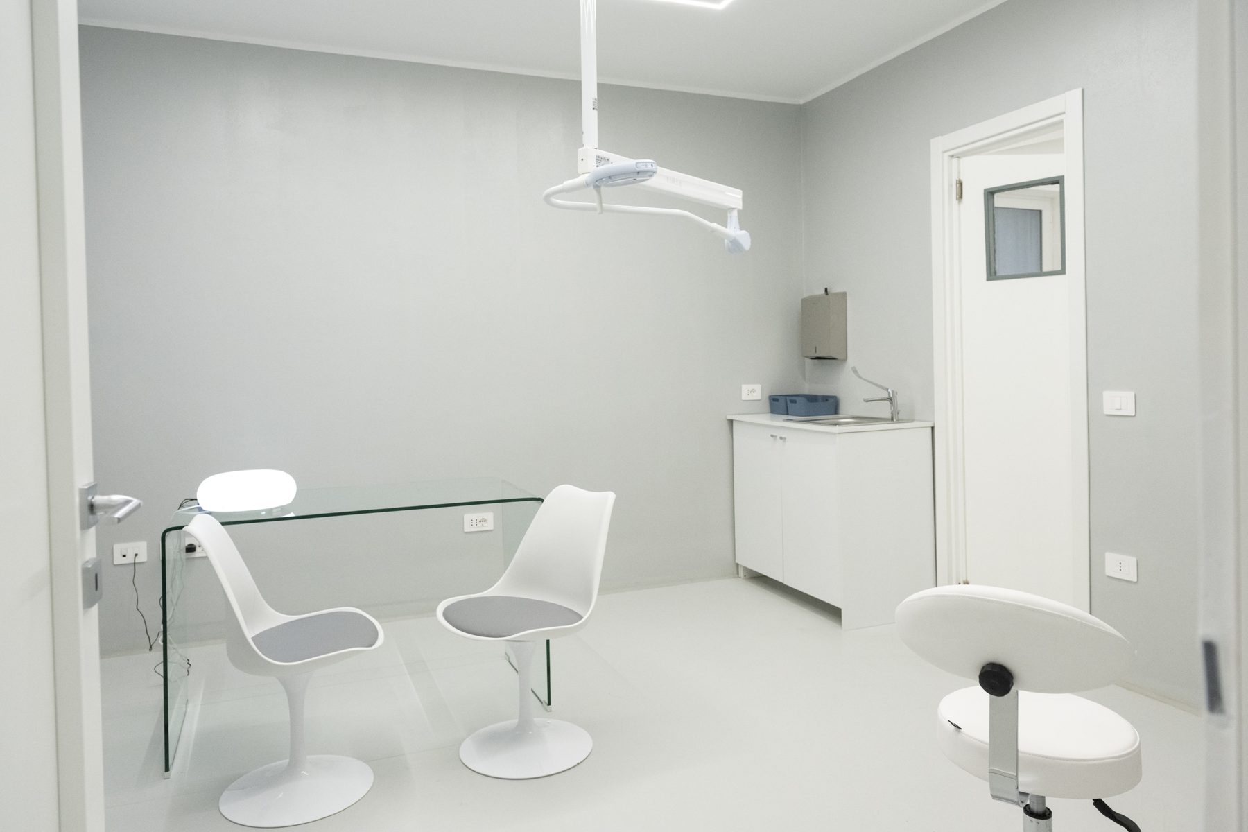 Una sala visita con scrivania in vetro