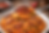 A spoonful of spicy octopus fried rice is held above a bowl of glossy red-orange rice, with detailed octopus tentacles, diced vegetables, and a softly blurred restaurant-style background.
