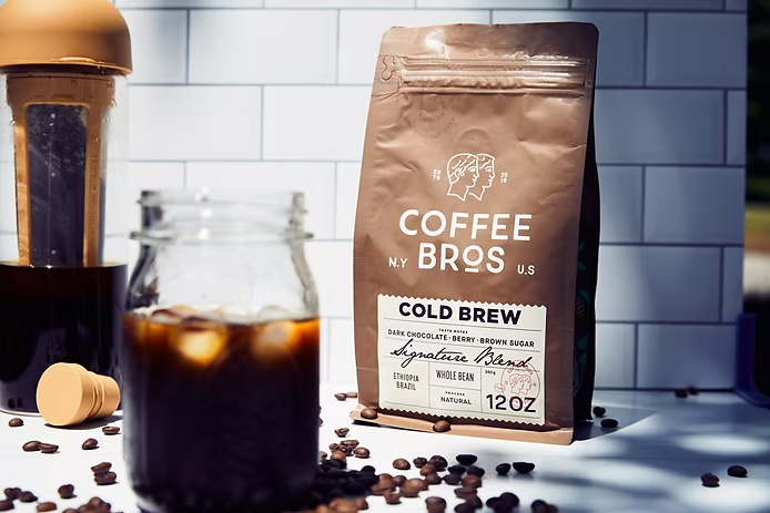 Cold brew coffee bottle and coffee bag displayed on a kitchen counter next to chestnut bread pairing setup.