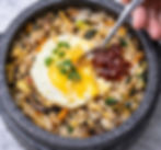 Mixed bibimbap in a hot stone bowl with rice, vegetables, beef, egg, and gochujang sauce