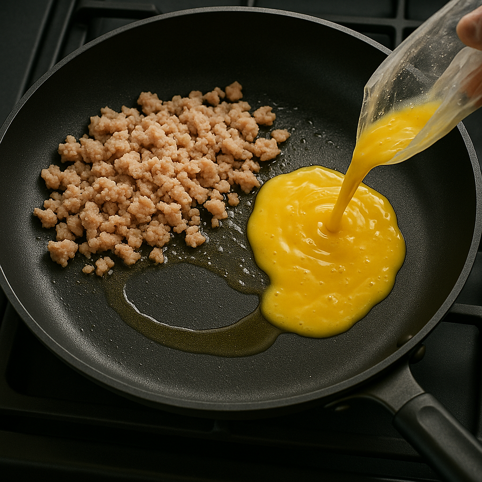 Cooked ground Spam on one side of a frying pan while beaten egg is being poured in beside it.
