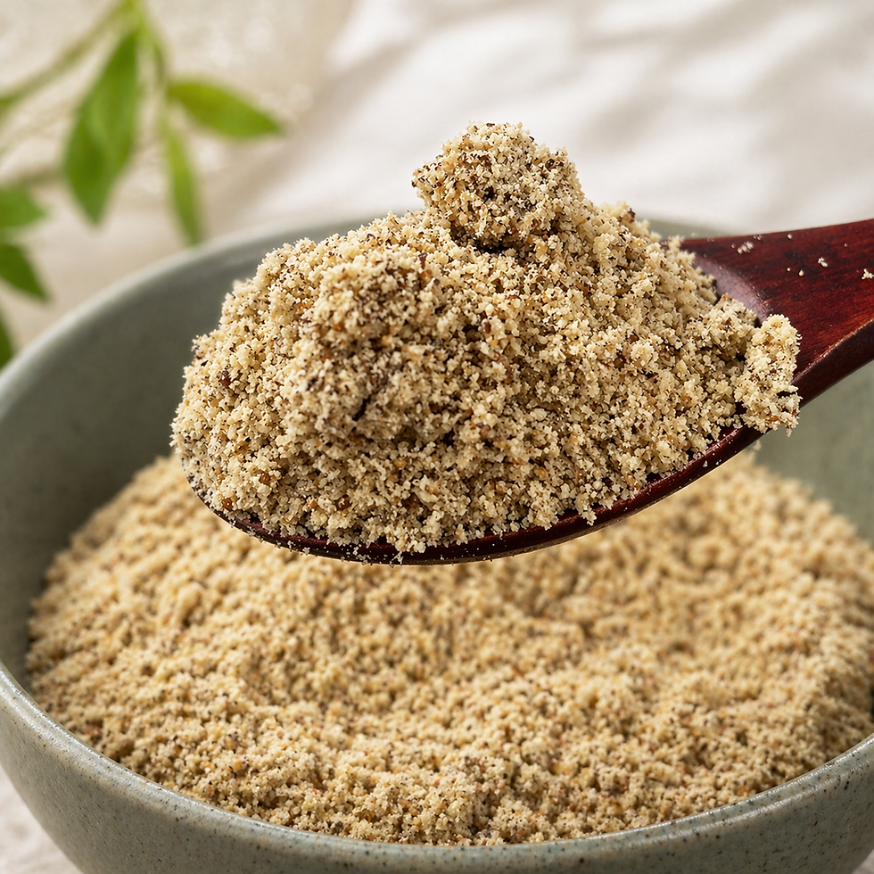 Close-up of ground deulkkae piled on a wooden spoon above a muted green ceramic bowl filled with more perilla seed powder, styled in a soft natural-light setting.