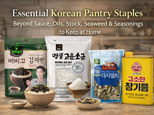 Premium landscape thumbnail for “Essential Korean Pantry Staples Beyond Sauce” featuring four Korean pantry items on a warm kitchen-style background: bibigo seasoned seaweed, HAIO natural sea salt, Dasi anchovy, and Ottogi sesame oil. Large headline text reads “Essential Korean Pantry Staples” with smaller supporting text about oils, stock, seaweed, and seasonings to keep at home. Small bowls of rice, seaweed, salt, and anchovies add a polished editorial look.