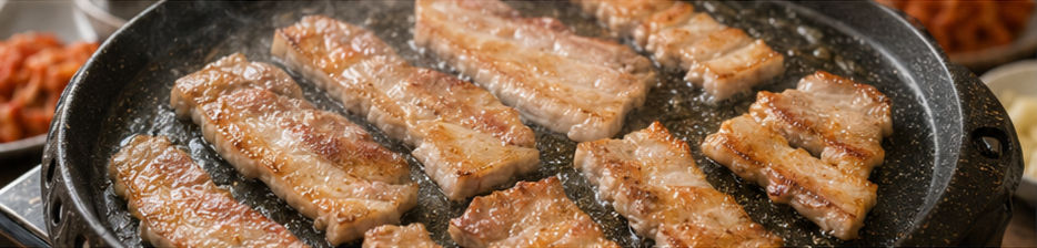 Pork belly slices browning on the grill pan with rendered fat and lightly crisped edges.