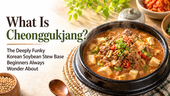 Bright morning-style blog thumbnail with a steaming black stone bowl of cheonggukjang stew filled with tofu, beef, soybeans, and red and green chili slices on the right, and large headline text on the left reading, “What Is Cheonggukjang? The Deeply Funky Korean Soybean Stew Base Beginners Always Wonder About.”