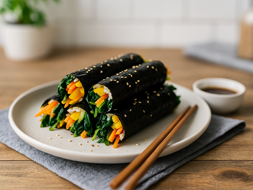 Korean mini kimbap (꼬마김밥) with spinach, carrot, and danmuji on a white plate, chopsticks beside.