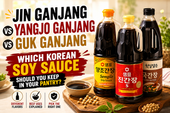 Bright Korean soy sauce guide thumbnail with three soy sauce bottles, a small dipping bowl, soybeans, and bold title text comparing jin ganjang, yangjo ganjang, and guk ganjang.