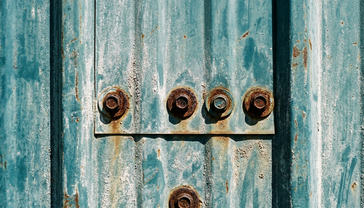 Close-up of faded metal siding with chalking near a fastener line