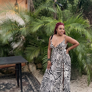 Woman standing at Habitas Tulum resort surrounded by tropical plants wearing a black and white dress