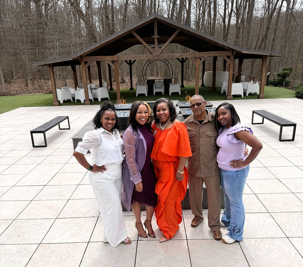 Family photo at an outdoor pavilion during a 60th birthday celebration featuring the birthday guest and loved ones posing together.