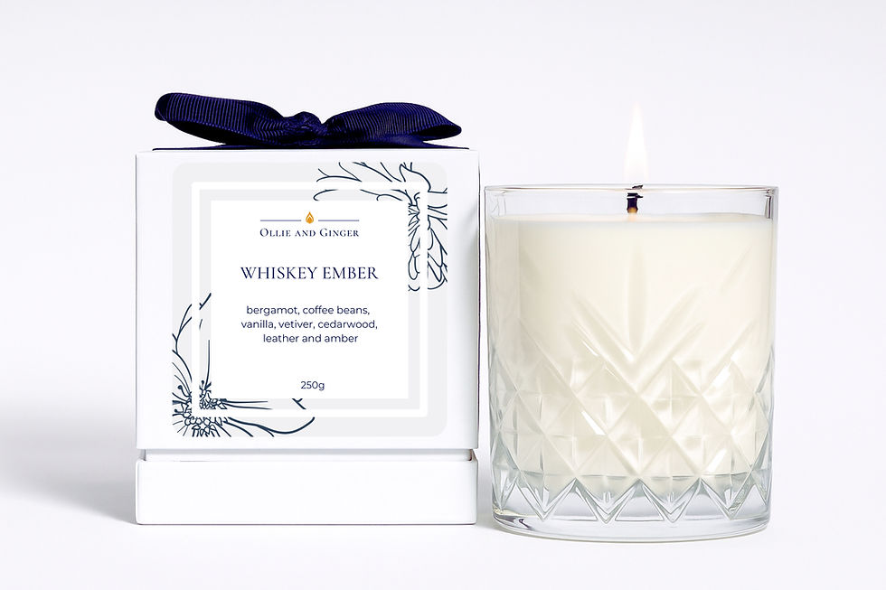 Ollie and Ginger Whiskey Ember scented candle next to its box tied with navy grosgrain ribbon, cocktail scented candles.