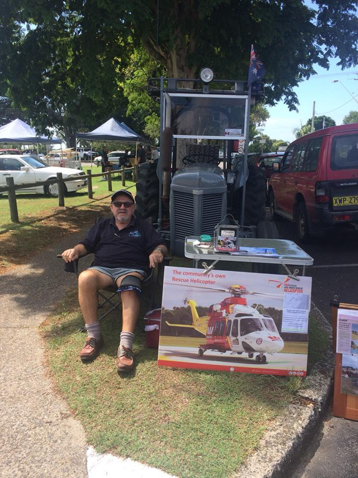 a man sits in front of a sign that says the community 's own rescue helicopter