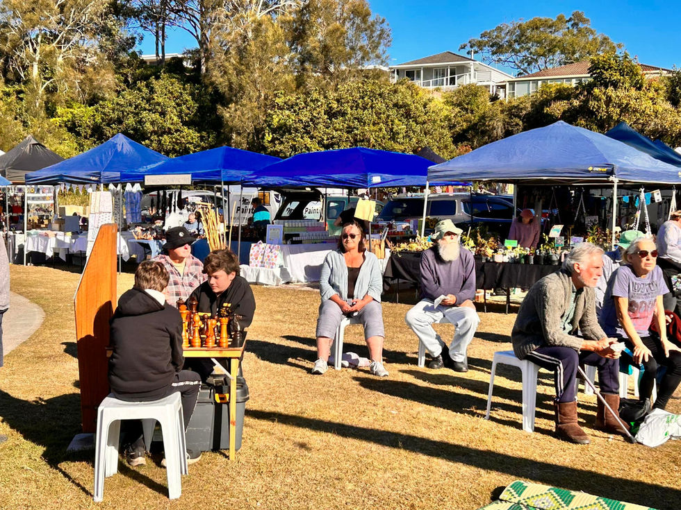 a group of people are sitting under blue tents at a market