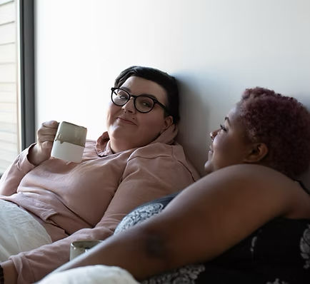 Two women reclining together in a relaxed, affectionate moment
