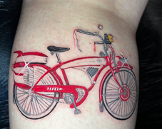 Custom color realism tattoo of the iconic red bicycle from a beloved cult classic 80s film, with fine detail linework and sparkle accents, designed and tattooed by Mandi at Wrapped in Plastic INK in Costa Mesa, Orange County, California.