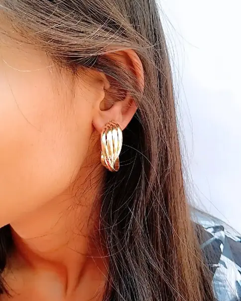Ear wearing a gold-toned bow hoop earring.