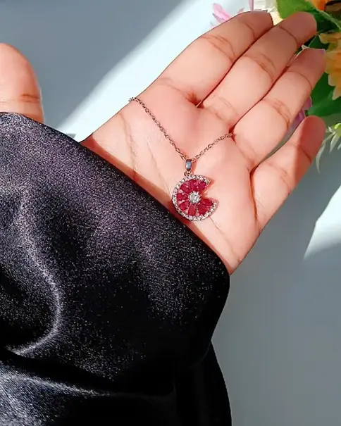 Hand holding a silver necklace with a pink tourmaline pendant