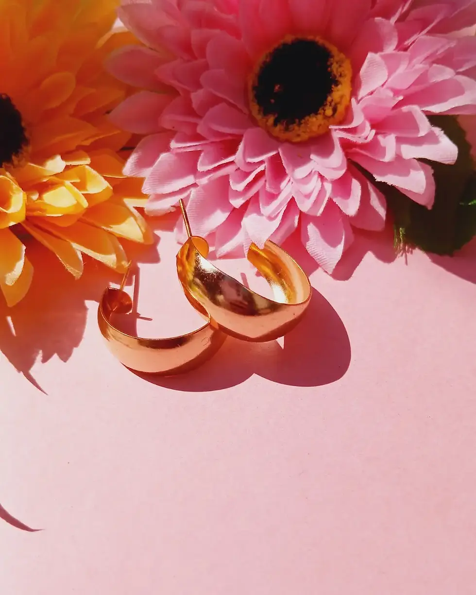 Gold hoop earrings on pink and orange flowers.