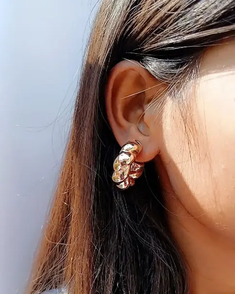 Ear wearing a rose gold twisted hoop earring.