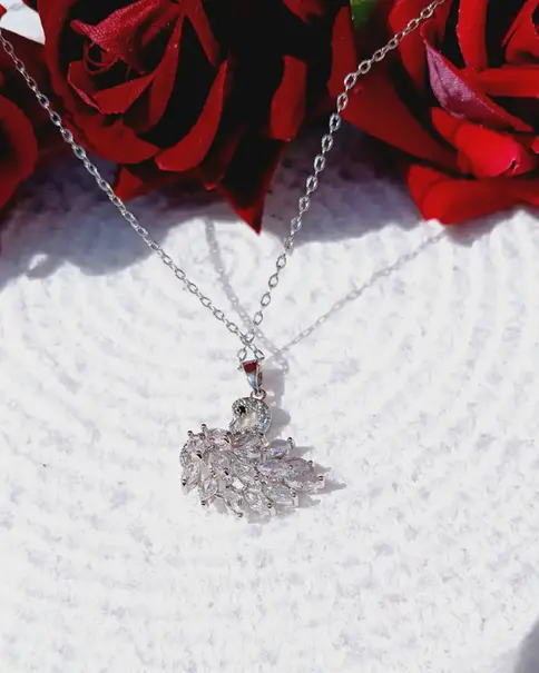Silver necklace with a clear gemstone swan pendant on a textured white background